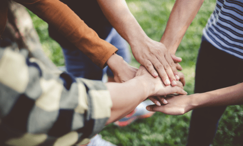 Volunteers putting their hands together, ready to support their community.